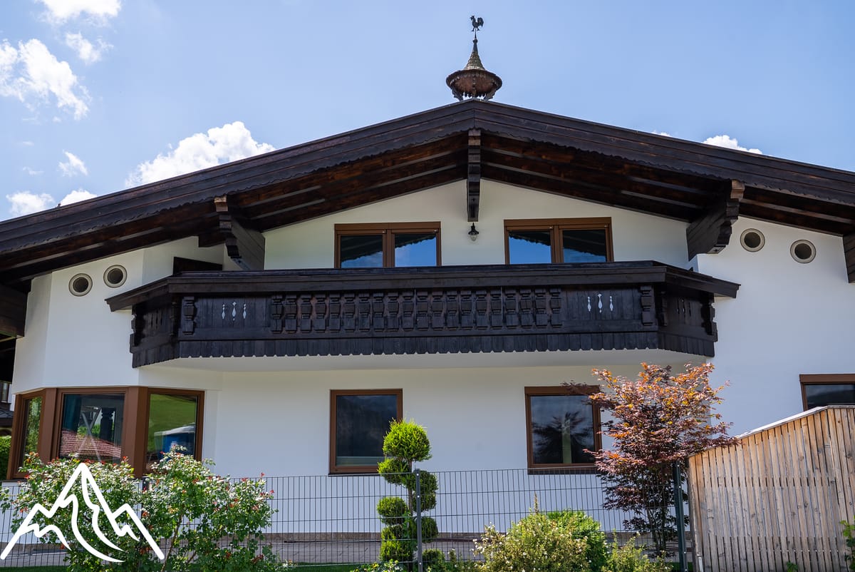 Tiroler Landhaus mit neuer weißer Fassade und dunkel lasiertem Holzbalkon